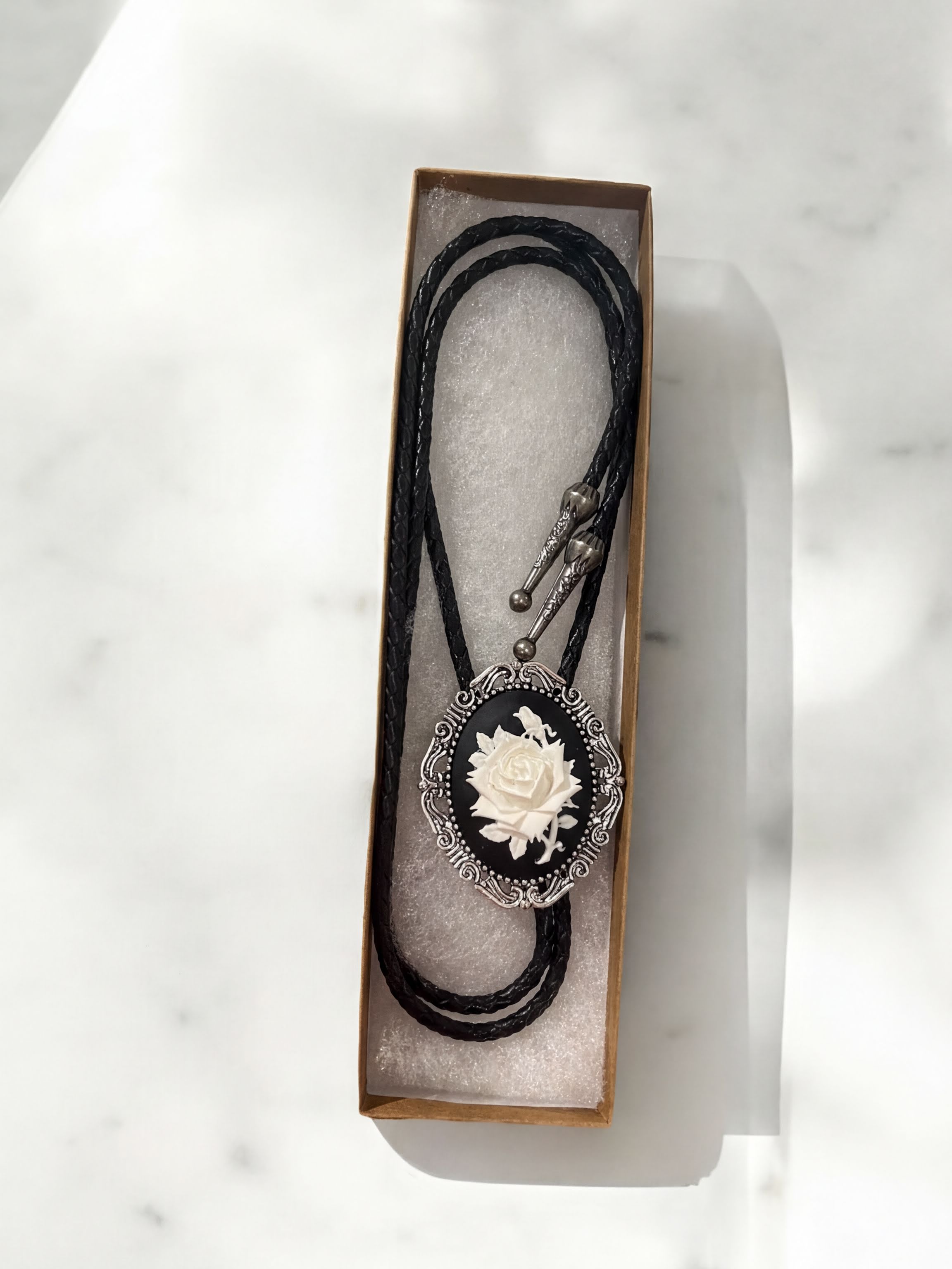 White rose silver bolo tie and leather cord.