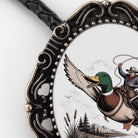 A decorative oval frame with a painting of a man riding a duck on a lasso, surrounded by a scenic landscape.