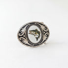 A decorative metal buckle featuring a fish image within an ornate frame.