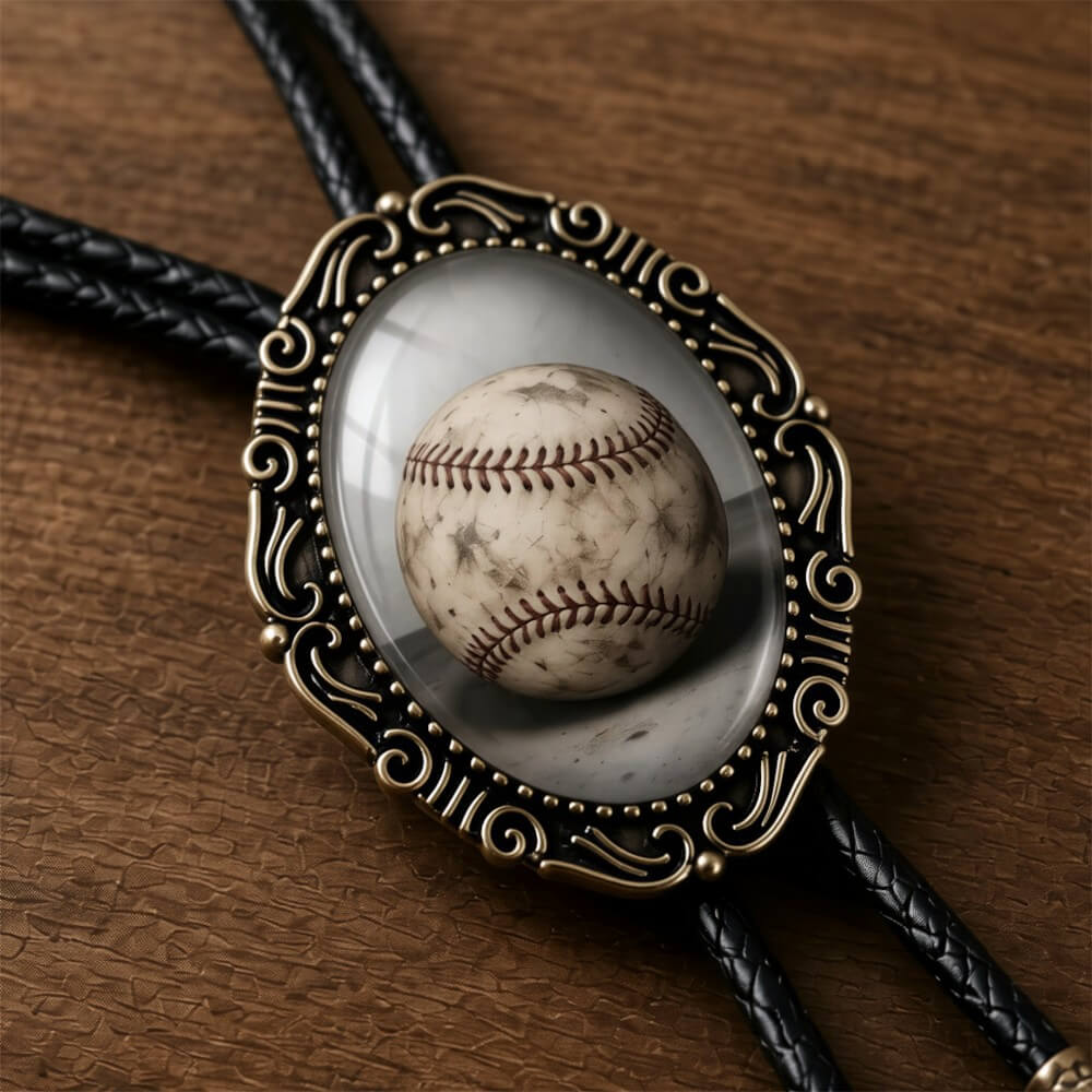 A baseball bolo tie for men and women displayed in a decorative oval-shaped frame on a wooden surface.