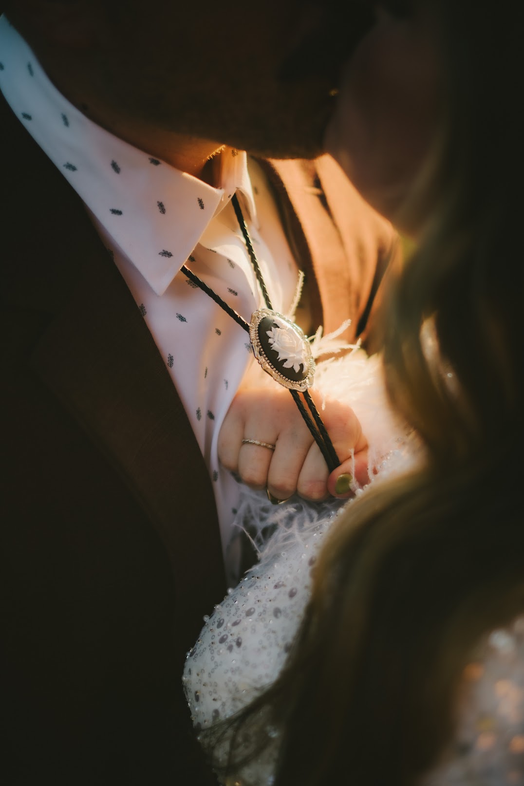 Close-up of a rose bolo tie worn by a person in a wedding.