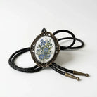 A decorative pendant featuring a floral design is displayed on a black leather cord.