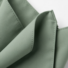 A close-up view of a green fabric, possibly a napkin or tablecloth, with a slight crease visible.