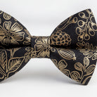 A close-up image of a black bow tie with a gold floral pattern.
