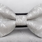 A close-up image of a silver dog bow tie with a floral pattern.