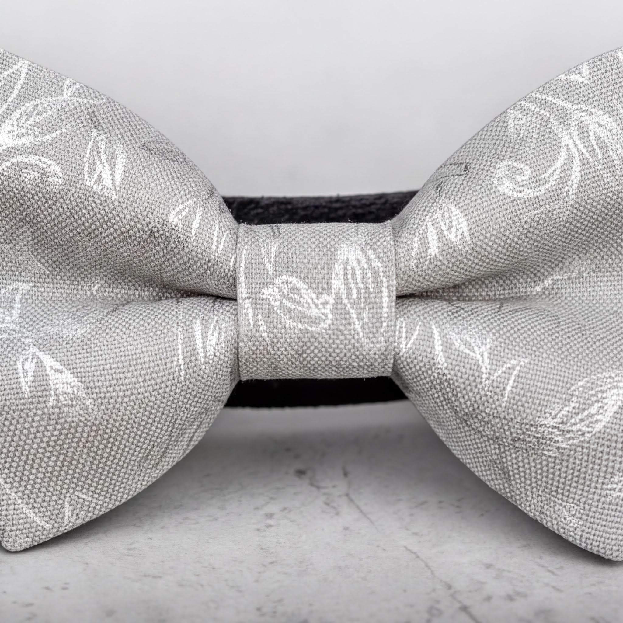 A close-up image of a silver dog bow tie with a floral pattern.