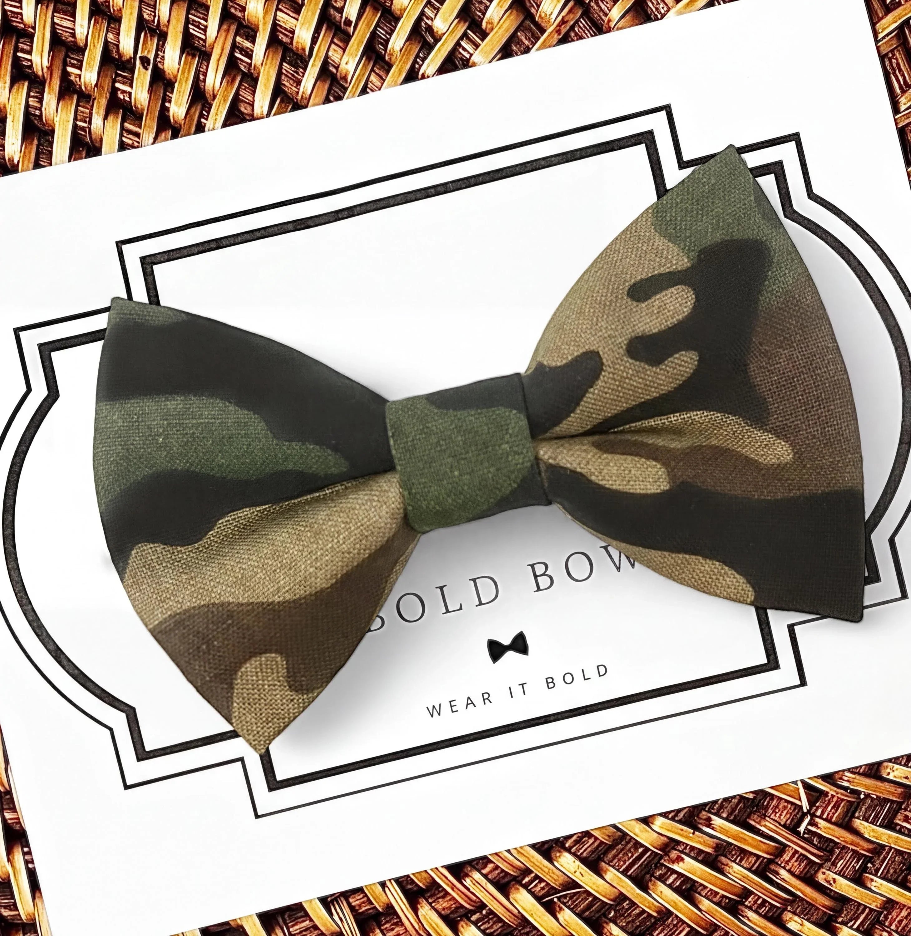 A camouflage bow tie is displayed on a white background with a black border.