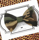 A camouflage bow tie is displayed on a white background with a black border.
