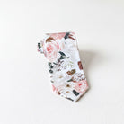 A tie with a floral print pattern, featuring white and pink flowers, is displayed against a white background.