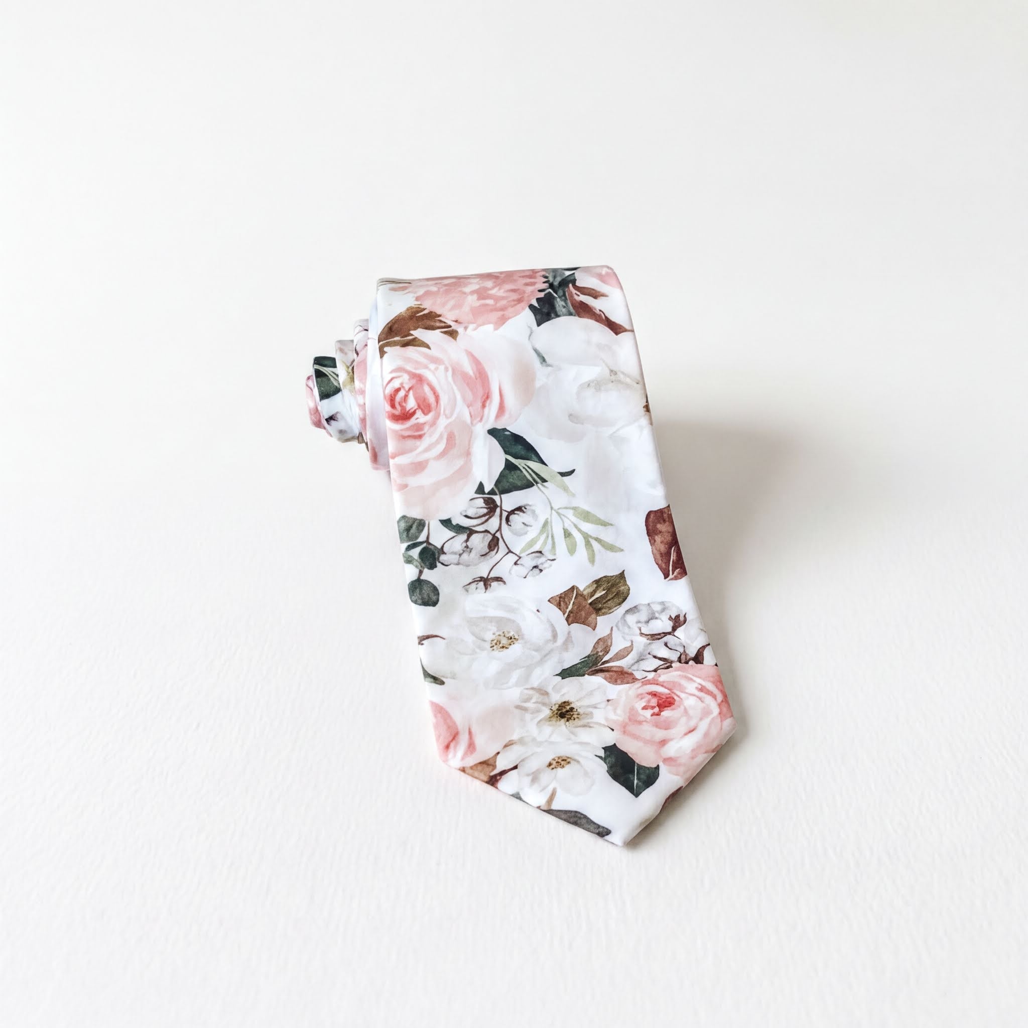 A tie with a floral print pattern, featuring white and pink flowers, is displayed against a white background.
