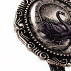 a decorative metal frame with an ornate design, and inside the frame is a detailed illustration of a black swan.
