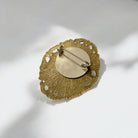 A brooch bronze pin with an ornate oval size, showing the finback of the brooch from The Bold Bow TIe.