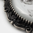 A close-up view of an ornate metal frame with a decorative design, featuring a central metal ball and intricate scrollwork.