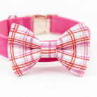 A pink collar with a bow tie featuring a plaid pattern.