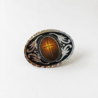 a decorative oval-shaped object with a cross at the center, surrounded by intricate floral designs.