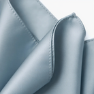 A close-up view of a light blue fabric, possibly a piece of clothing or a decorative item, with a slightly curled and folded appearance.