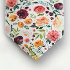 a close-up view of a tie with a floral pattern, including various types of flowers and leaves.