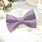 Size chart for pre-tied bow ties from The Bold Bow Tie detailing measurements across three sizes. Small is 3.5 inches wide and recommended for ages 6 months to 5 years. Medium is 4 inches wide and recommended for ages 6 to 12 years. Large is 4.5 inches wide and recommended for ages 13 years and up. Visual icons illustrate the relative sizes with horizontal arrows showing that width is measured from wingtip to wingtip. Bottom text notes that all bow ties are pre-tied and ready to add to your outfit.