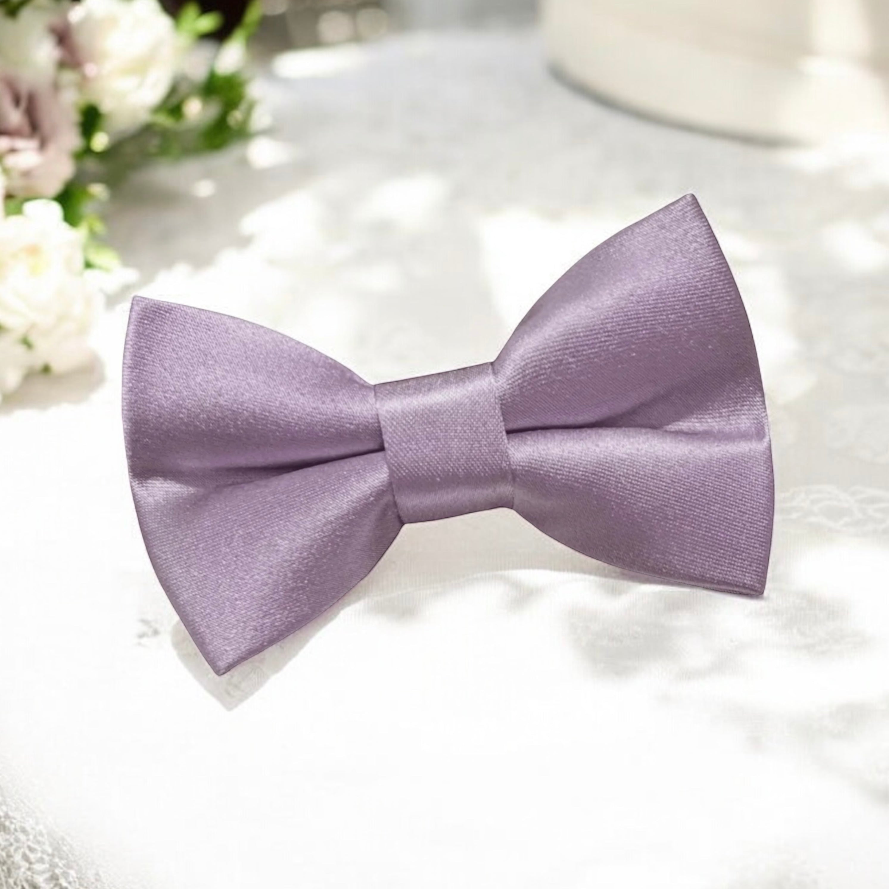Size chart for pre-tied bow ties from The Bold Bow Tie detailing measurements across three sizes. Small is 3.5 inches wide and recommended for ages 6 months to 5 years. Medium is 4 inches wide and recommended for ages 6 to 12 years. Large is 4.5 inches wide and recommended for ages 13 years and up. Visual icons illustrate the relative sizes with horizontal arrows showing that width is measured from wingtip to wingtip. Bottom text notes that all bow ties are pre-tied and ready to add to your outfit.