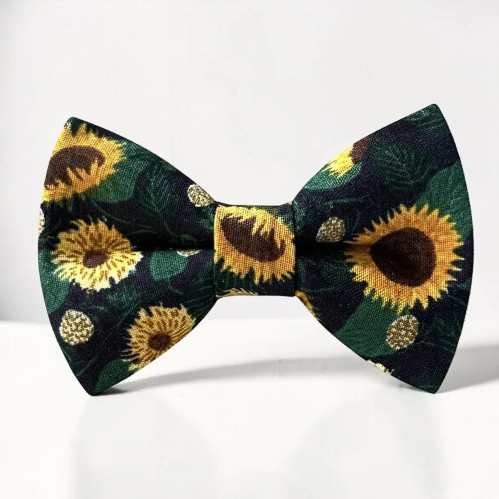The Bold Bow Tie pre-tied cotton bow tie featuring a vibrant yellow sunflower floral pattern on a dark green background.