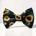 The Bold Bow Tie pre-tied cotton bow tie featuring a vibrant yellow sunflower floral pattern on a dark green background.