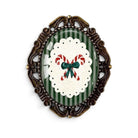 The Bold Bow Tie vintage-style Christmas brooch featuring candy canes on a green striped background in a bronze frame.