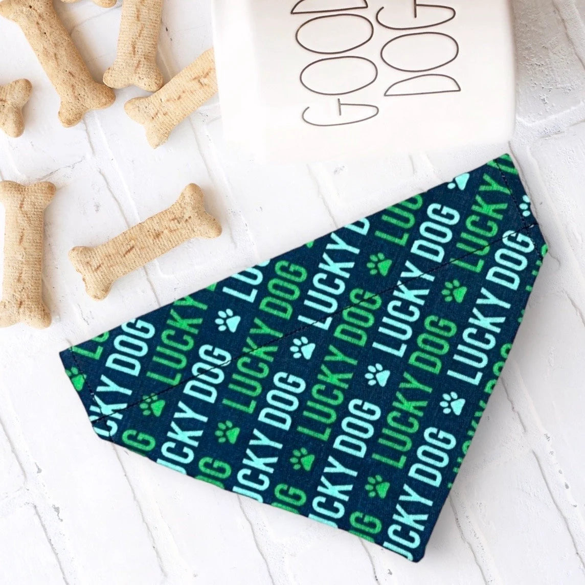 a dog bandana laying on a white table next to a dog bone