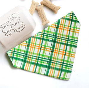 a green and yellow plaid napkin next to a dog bone and a glass of milk