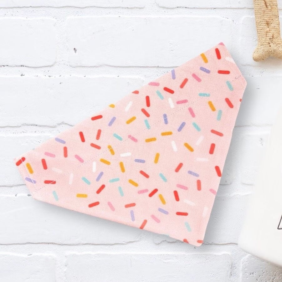 a pink napkin with sprinkles on it next to a cup of coffee
