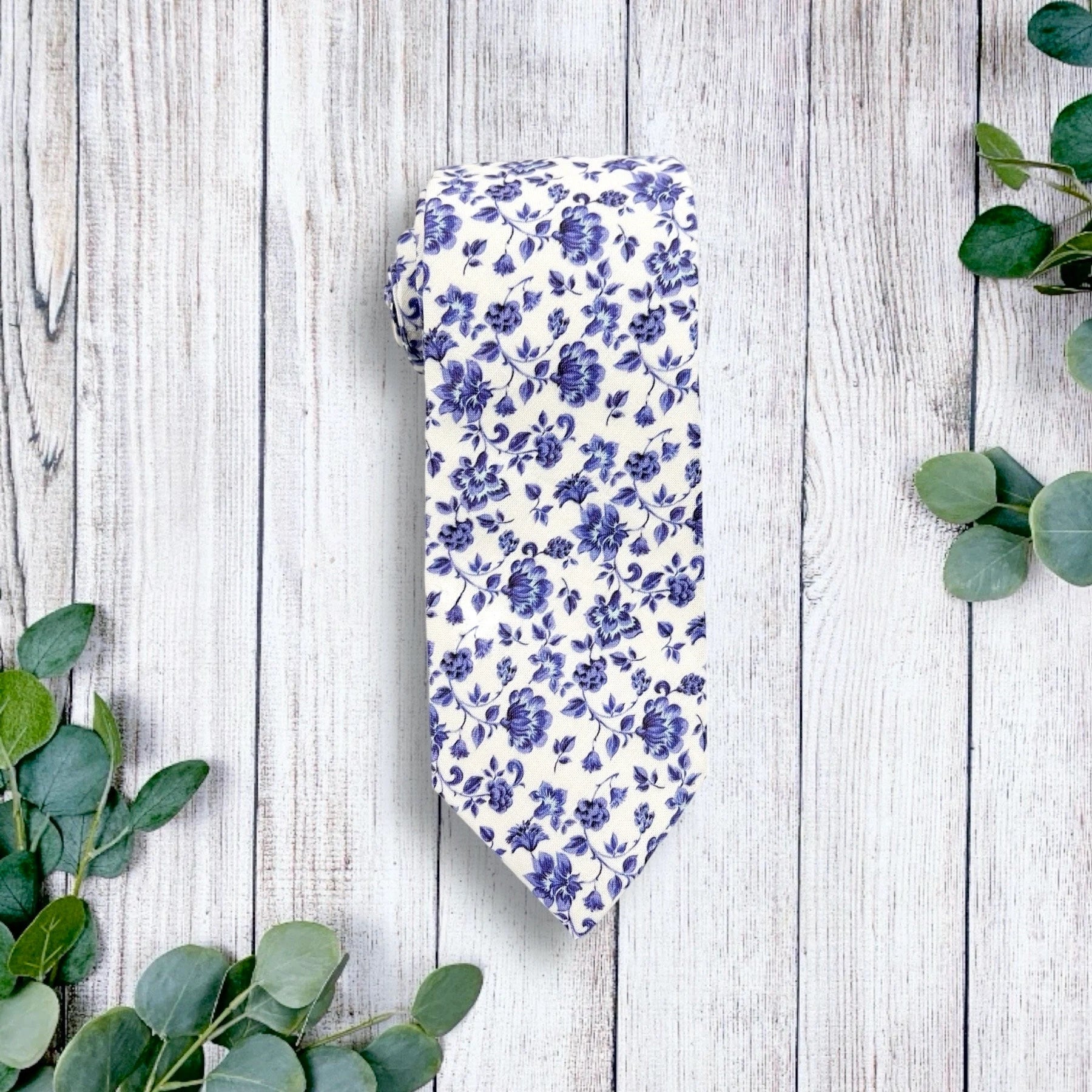 a blue and white floral tie laying on top of a wooden floor